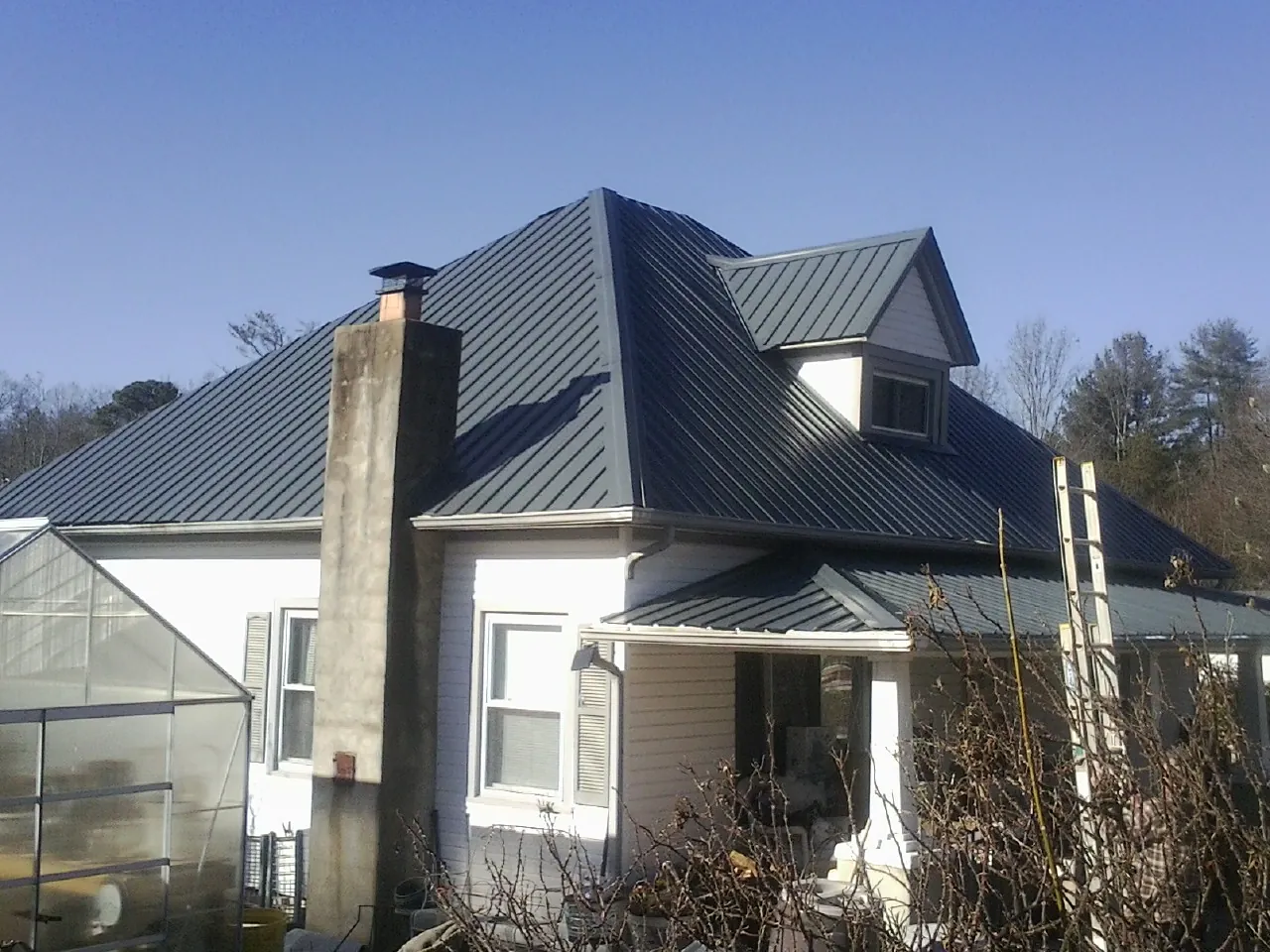 Dark blue standing seam metal roof on a white farmhouse with dormer — Slate & Tile Roof Repair by Roofing Brothers in Freedom