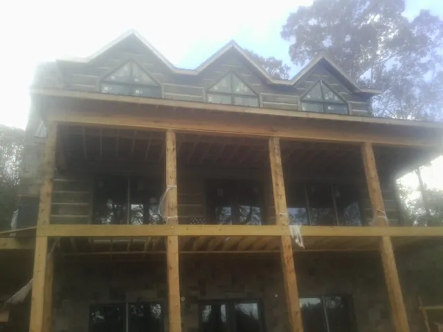 Dormers and porch framing on a large log home under construction — Roof Coating work by our crew in Freedom